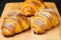 close-up-three-freshly-baked-croissants-sugar-powder-wooden-desk-puff-french-pastry-182644148
