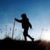 silhouette-of-little-boy-walking-on-a-meadow-at-backlight-picture-id642114501