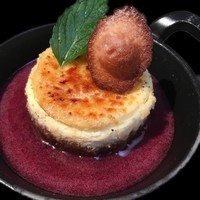 crème brûlée comme un cheesecake servie avec un coulis de fruits rouges et une petite madeleine