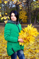 56119390-Single-seus-woman-in-green-coat-looking-down-at-bundle-of-maple-leaves-in-her-hands-at-park