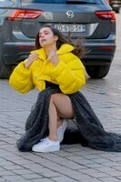 sofia-carson-pose-for-photos-in-a-bright-yellow-puffer-jacket-with-a-black-dress-and-white-sneakers-