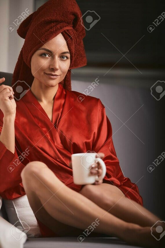 138521852-model-in-a-red-bathrobe-and-a-red-towel-on-the-sofa-with-a-coffee-mug-and-a-lollipop-the-c